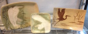 Display of stoneware platters and plate, sgraffito carved egrets