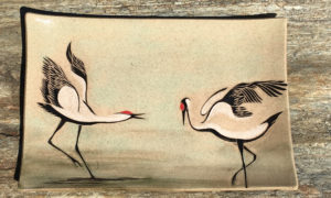 Stoneware platter, sgraffito carved dancing cranes design